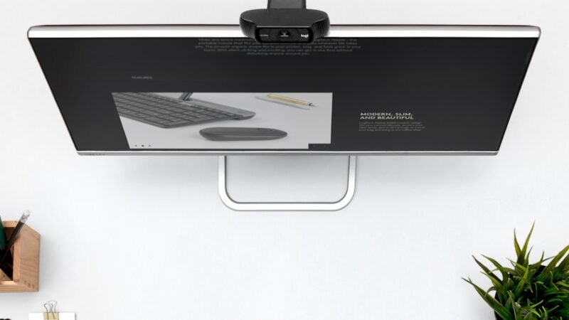 Webcam montada sobre um monitor em uma estação de trabalho preparada para videochamadas.